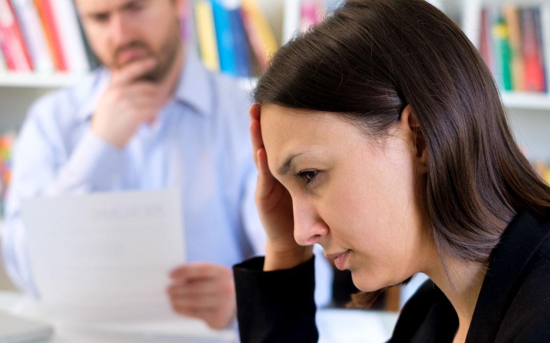 a woman sitting in an interview with her hand on her head, looking stressed